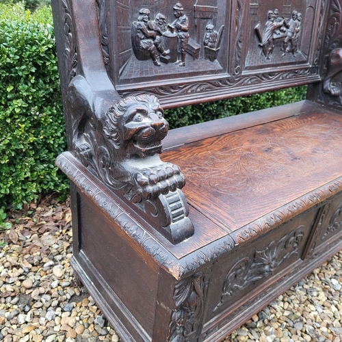 329 - A VICTORIAN OAK TWO SEAT SETTLE
With facial mask finials above panels carved with tavern scenes, arm... 