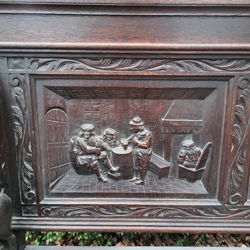 329 - A VICTORIAN OAK TWO SEAT SETTLE
With facial mask finials above panels carved with tavern scenes, arm... 