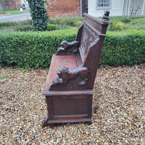 329 - A VICTORIAN OAK TWO SEAT SETTLE
With facial mask finials above panels carved with tavern scenes, arm... 