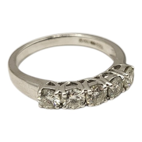 83 - AN 18CT WHITE GOLD AND DIAMOND FIVE STONE RING
The row of round cut diamonds set in a plain design, ... 