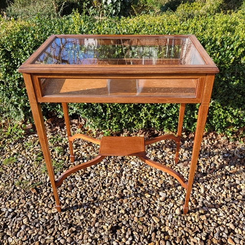 351 - AN EDWARDIAN MAHOGANY AND LINE INLAID BIJOUTERIE TABLE
The glazed top raised on square tapering legs... 