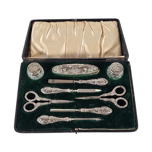 94 - AN EARLY 20TH CENTURY SILVER ‘REYNOLDS ANGELS’ MANICURE SET
To include two glass rouge pots ,nail sc... 