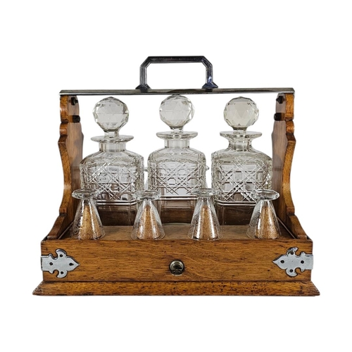 29 - A VICTORIAN OAK,SILVER PLATE AND CUT LEAD CRYSTAL GLASS TANTALUS
Three square cut glass decanters, d... 