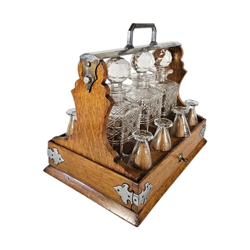 29 - A VICTORIAN OAK,SILVER PLATE AND CUT LEAD CRYSTAL GLASS TANTALUS
Three square cut glass decanters, d... 