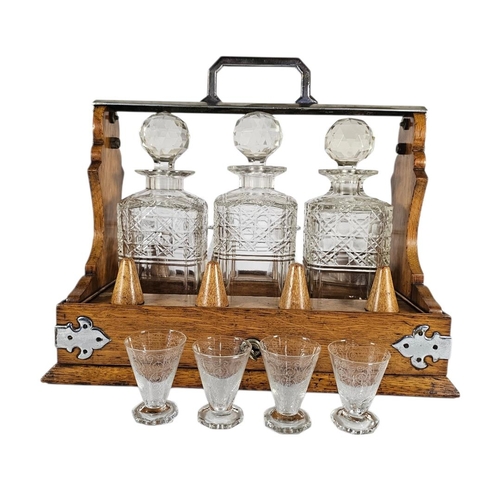 29 - A VICTORIAN OAK,SILVER PLATE AND CUT LEAD CRYSTAL GLASS TANTALUS
Three square cut glass decanters, d... 