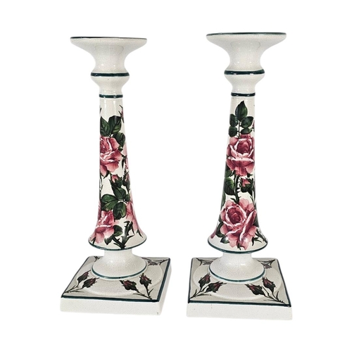 41 - WEMYSS WARE, A PAIR OF EARLY 20TH CENTURY 'CABBAGE ROSE' POTTERY CANDLESTICKS
Tall form with pink bl... 