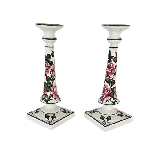41 - WEMYSS WARE, A PAIR OF EARLY 20TH CENTURY 'CABBAGE ROSE' POTTERY CANDLESTICKS
Tall form with pink bl... 