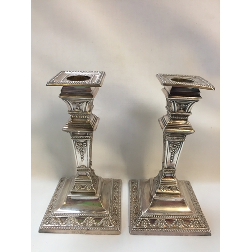 344 - PAIR OF NEO CLASSICAL SILVER CANDLESTICKS ON SQUARE TAPERING STEMS EMBOSSED GARLANDS AND RIBBONS, SQ... 