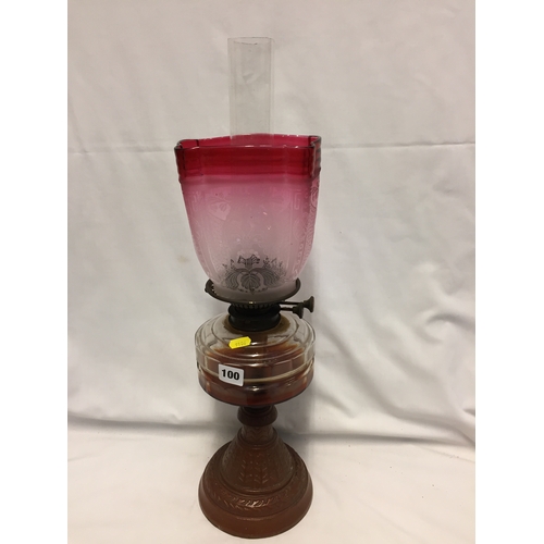 100 - VICTORIAN GLASS OIL LAMP ON EMBOSSED CAST IRON BASE WITH ETCHED CRANBERRY GLASS SHADE