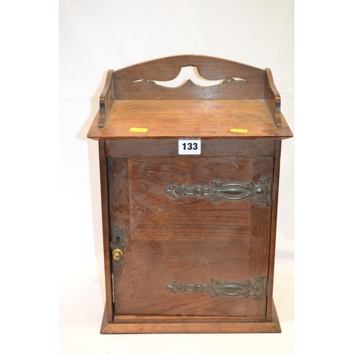 133 - EDWARDIAN OAK SMOKERS CABINET FITTED PIPE RACKS ENCLOSED BY DOOR WITH METAL STRAPWORK HINGES, PIERCE... 