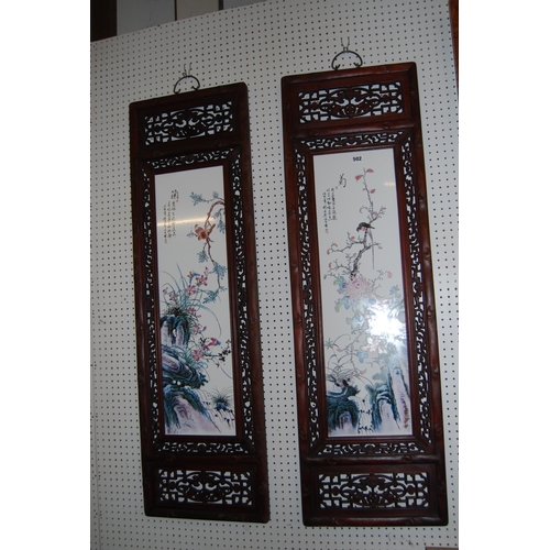 502 - PAIR OF CHINESE CERAMIC WALL PLAQUES HAND PAINTED BIRDS AND FLOWERS, IN CARVED HARDWOOD FRAMES