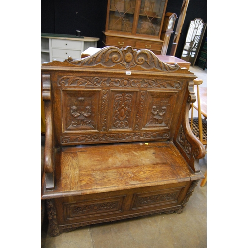 633 - 19TH CENTURY RICHLY CARVED OAK HALL SETTLE WITH BOX SEAT, CARVED PANEL BACK AND CRESTING RAIL