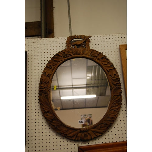 587 - OVAL WALL MIRROR IN FRAME CARVED WITH LEAVES & BERRIES SURMOUNTED BIRD