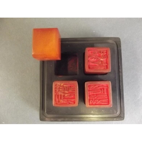 33 - A Chinese hardstone box containing four amber stone seals, the lid with carved gourd decoration, sea... 