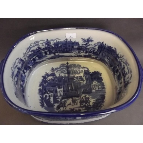 7 - A large blue and white pottery foot bath decorated with figures and classical buildings, 18