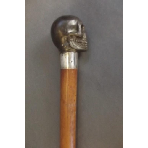 27 - A polished Malacca walking stick with cast bronze handle in the form of a skull, 36