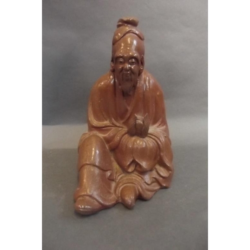 88 - An Oriental glazed terracotta figure of a sage holding a peach whilst seated, 9