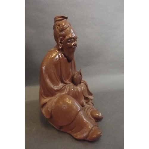 88 - An Oriental glazed terracotta figure of a sage holding a peach whilst seated, 9