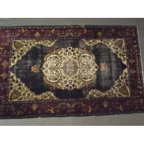 911 - A Persian hand woven wool rug with central medallion design on a blue field, with red borders decora... 