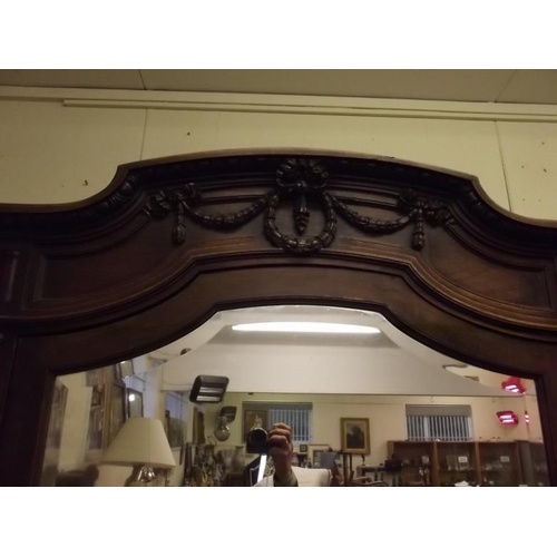 915 - An imposing Italian walnut breakfront armoire with bevelled mirror doors and carved classical decora... 