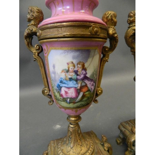 50N - A pair of pink ground Sevres style side urns with ormolu mounts and painted decoration of courting c... 