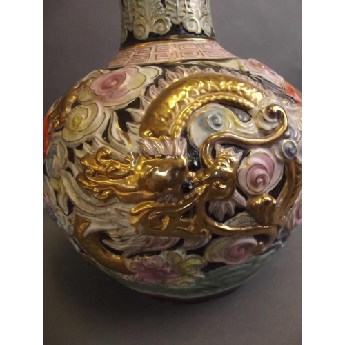 50V - A large Chinese porcelain long necked vase, the bulbous base with embossed dragon and floral decorat... 