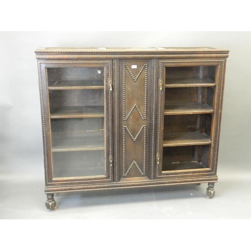 827 - A Victorian oak two door glazed bookcase with carved bead decoration, on shaped supports, 60