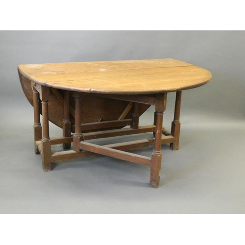 832 - A C19th oak drop leaf dining table with gate leg supports and single end drawer, 16