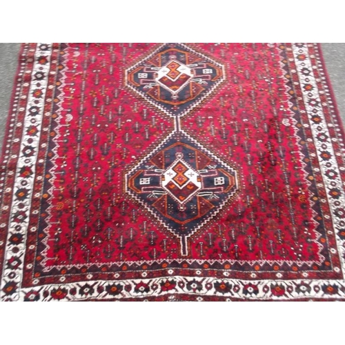 835 - A Persian wool carpet with central lozenge design on a red field with ivory borders, 86