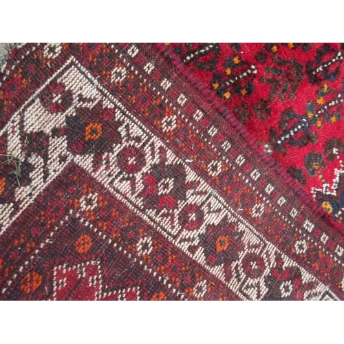 835 - A Persian wool carpet with central lozenge design on a red field with ivory borders, 86