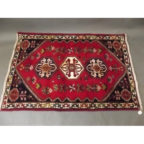 854 - A Persian wool rug with geometric design on a bright red field, 63