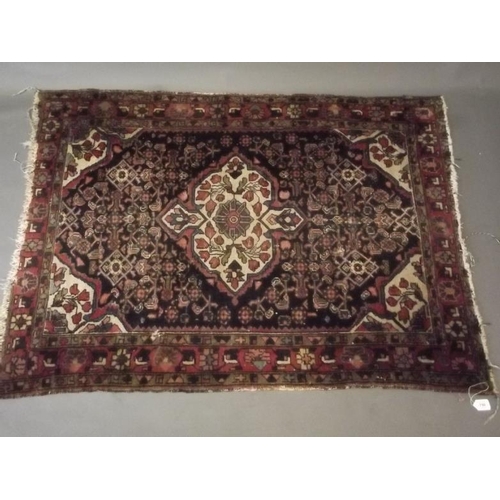 859 - A Persian rug with central medallion design on a blue field with red borders, and all over stylised ... 