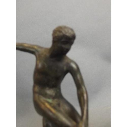 24 - A small bronze figure of a discus thrower, on a circular base, 5½