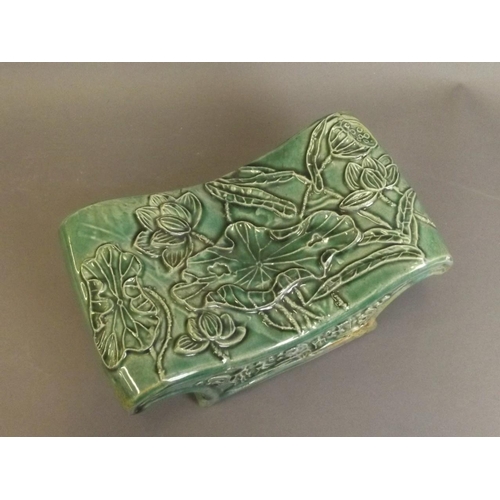 23 - A Chinese green crackle glazed porcelain head rest with relief lotus flower and lily decoration, 9½