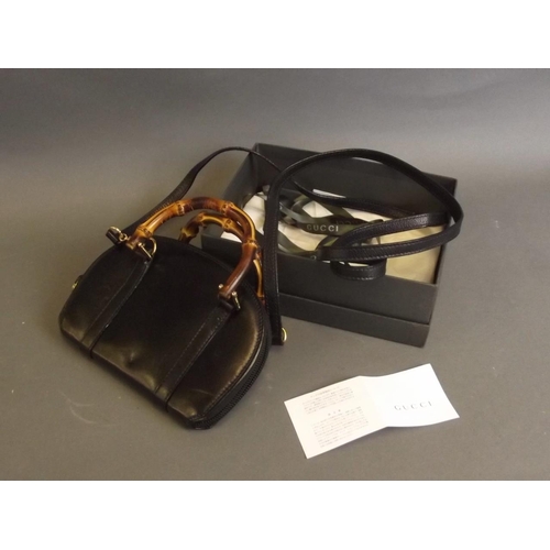 50Q - A small leather designer handbag by Gucci with cane handles, boxed, 7