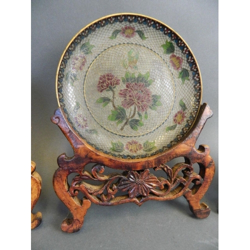 21 - A garniture of three Chinese plique-à-jour saucer dishes with floral decoration, on carved wood stan... 