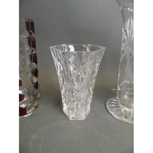 48 - A collection of three cut glass vases, together with a pair of triform crystal vases with cranberry ... 