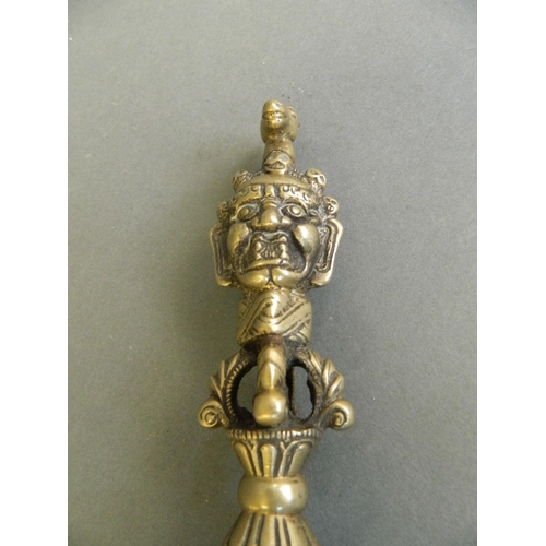 103 - A Sino-Tibetan brass phurba with vajra and deity mask decoration to handle, 9½