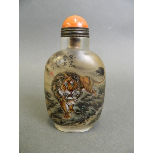 134 - A Chinese glass snuff bottle with reverse painted decoration of prowling lions, 3½