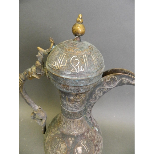 150B - An Islamic bronze pourer with silver and copper inlaid script decoration, 14½