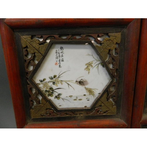 184 - A pair of Chinese porcelain and carved hardwood panels containing four famille verte plaques depicti... 