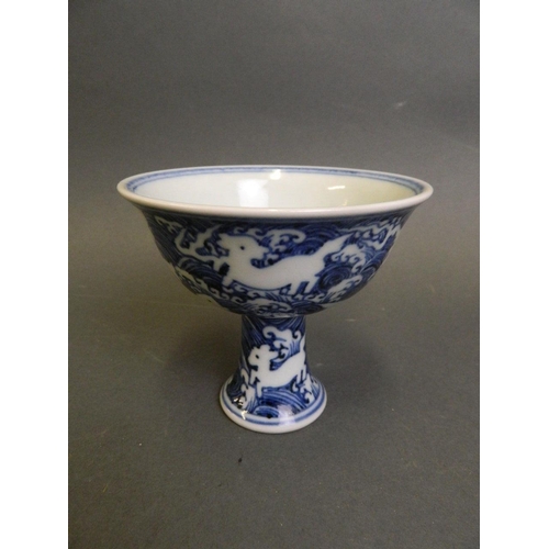 210 - A Chinese blue and white porcelain stem cup with incised decoration of mythical creatures above wave... 