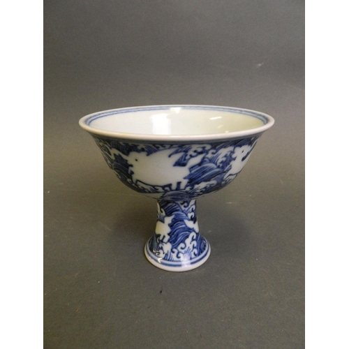 210 - A Chinese blue and white porcelain stem cup with incised decoration of mythical creatures above wave... 