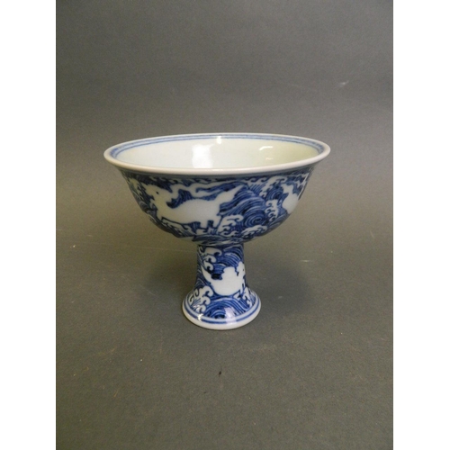 210 - A Chinese blue and white porcelain stem cup with incised decoration of mythical creatures above wave... 