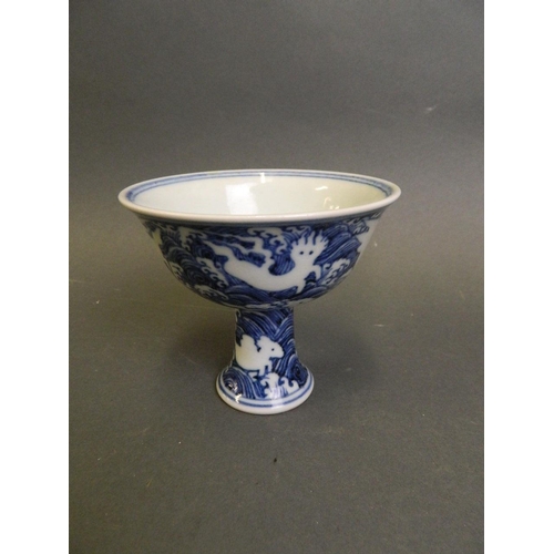 210 - A Chinese blue and white porcelain stem cup with incised decoration of mythical creatures above wave... 