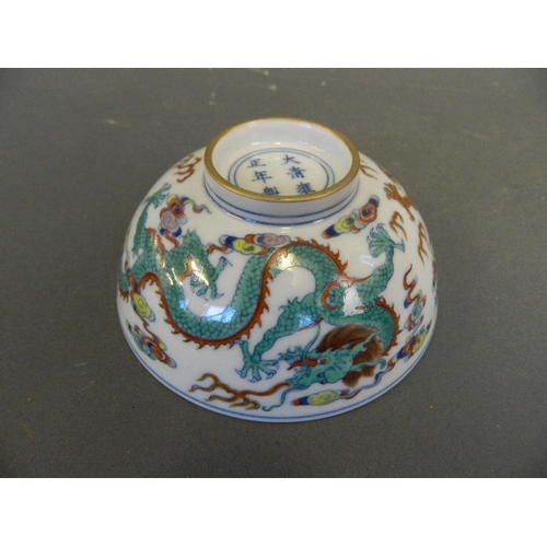 211 - A Chinese Doucai enamelled porcelain rice bowl decorated with twin dragons chasing the flaming pearl... 