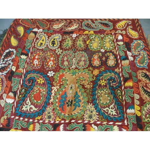 250Y - An Uzbek Suzani wall hanging with embroidered silk decoration on a deep red field, 54