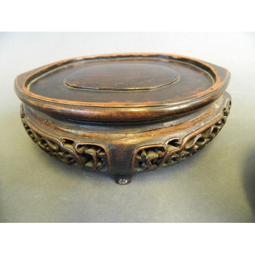 257 - A Chinese oval pierced and carved hardwood stand, together with a similar circular stand, and anothe... 