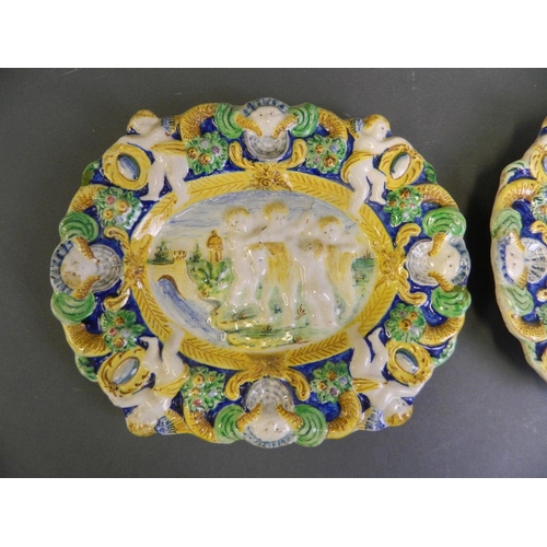 73 - A pair of antique Majolica plaques decorated with Putti herding goats, 11½