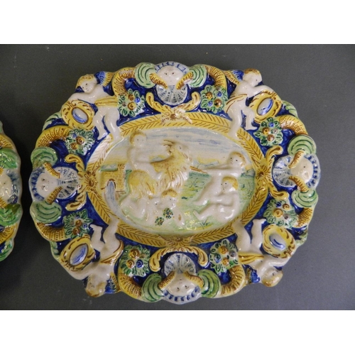 73 - A pair of antique Majolica plaques decorated with Putti herding goats, 11½